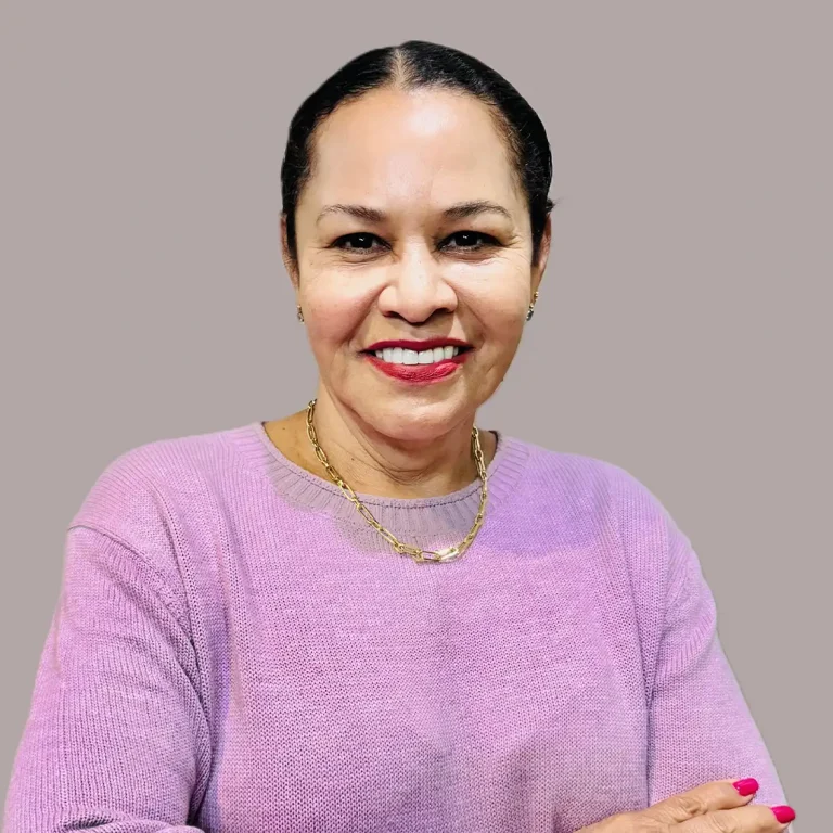 A smiling person in a pink sweater against a plain gray background.